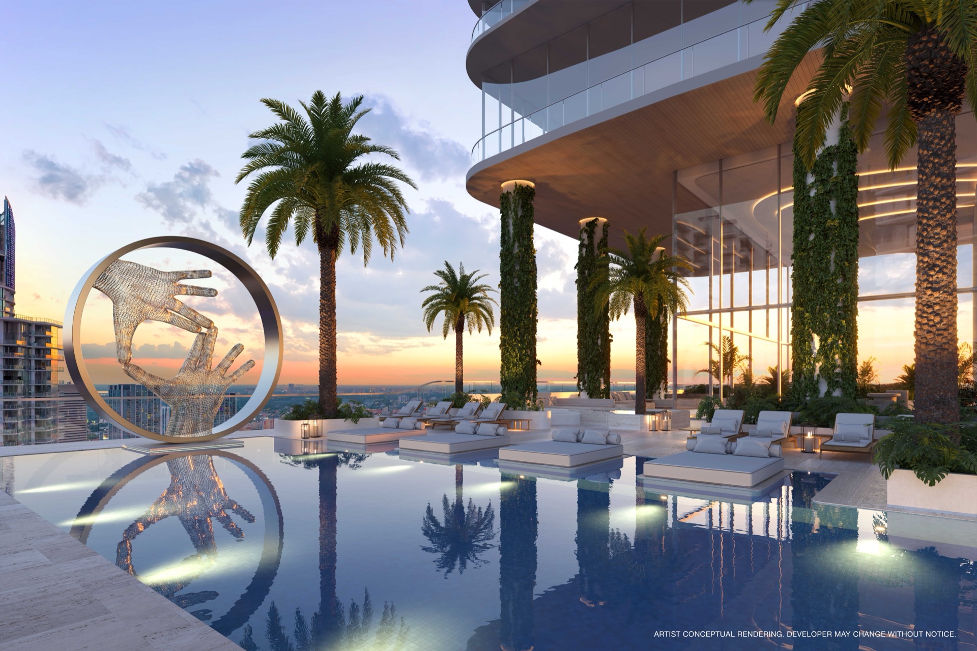 The JEM Club resort pool at sunset — cabanas, floating daybeds, a signature sculpture, and palm-framed views over Miami from the 50th-floor amenity deck at JEM Residences Miami.